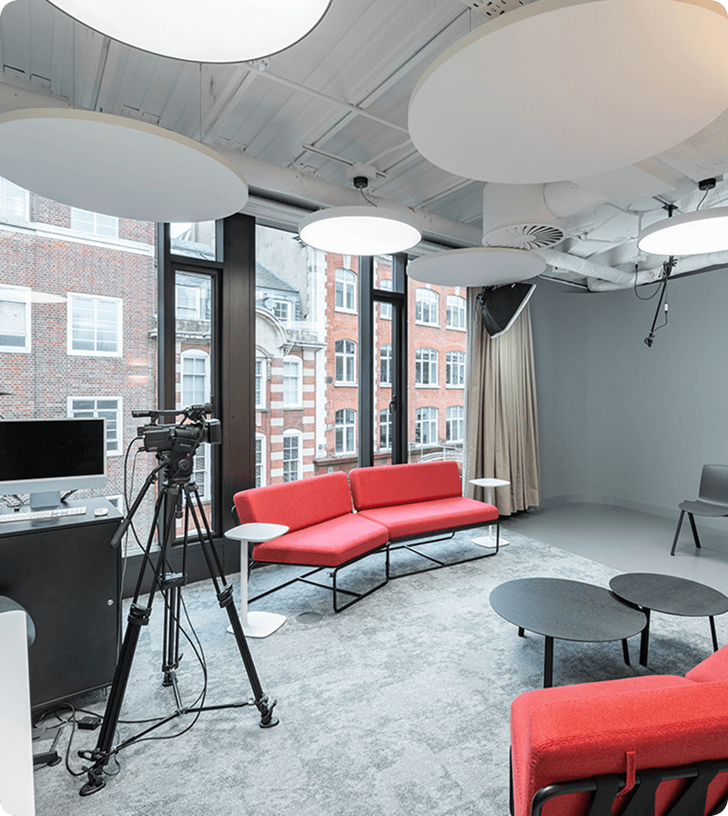 Modern studio space with red sofa, camera on tripod, and large windows