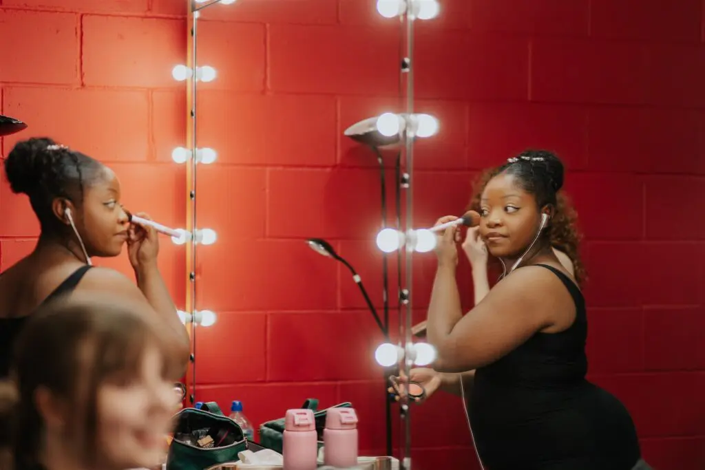 Lady putting on makeup in front of mirror