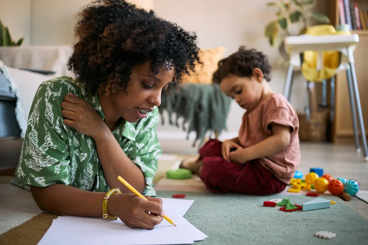 Mother making notes on a script while her young son plays next to her