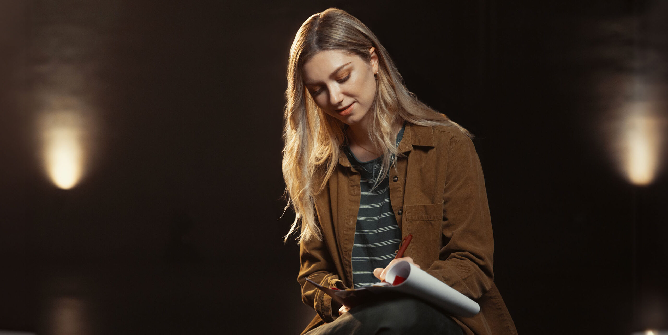 A young performer makes notes in a script.