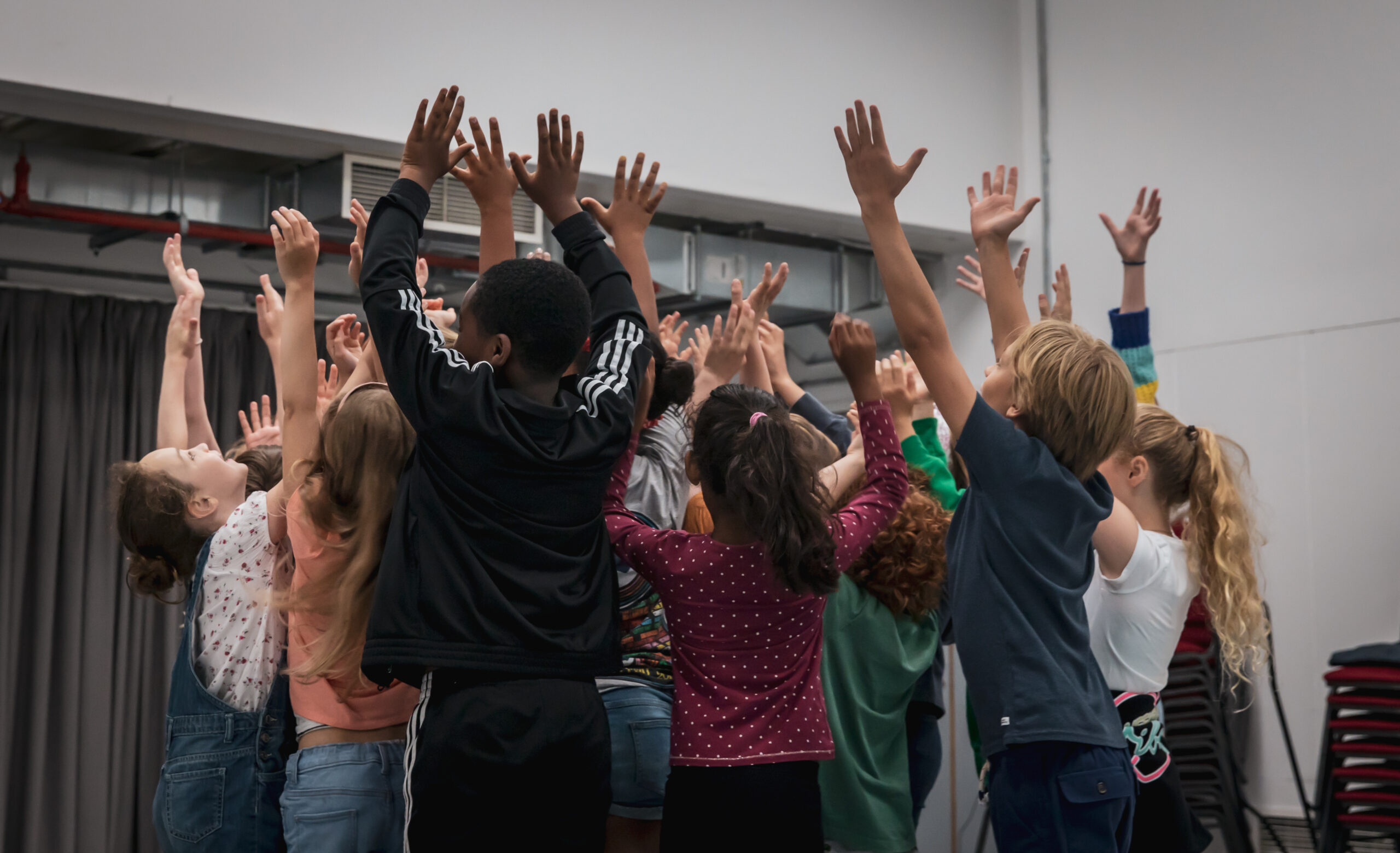 A group of young performers with their arms in the air