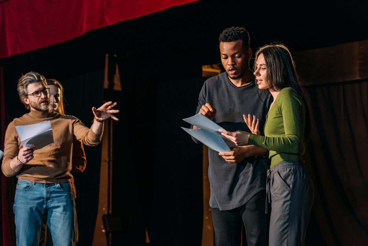 A theatre director, actor and actress rehearsing on stage