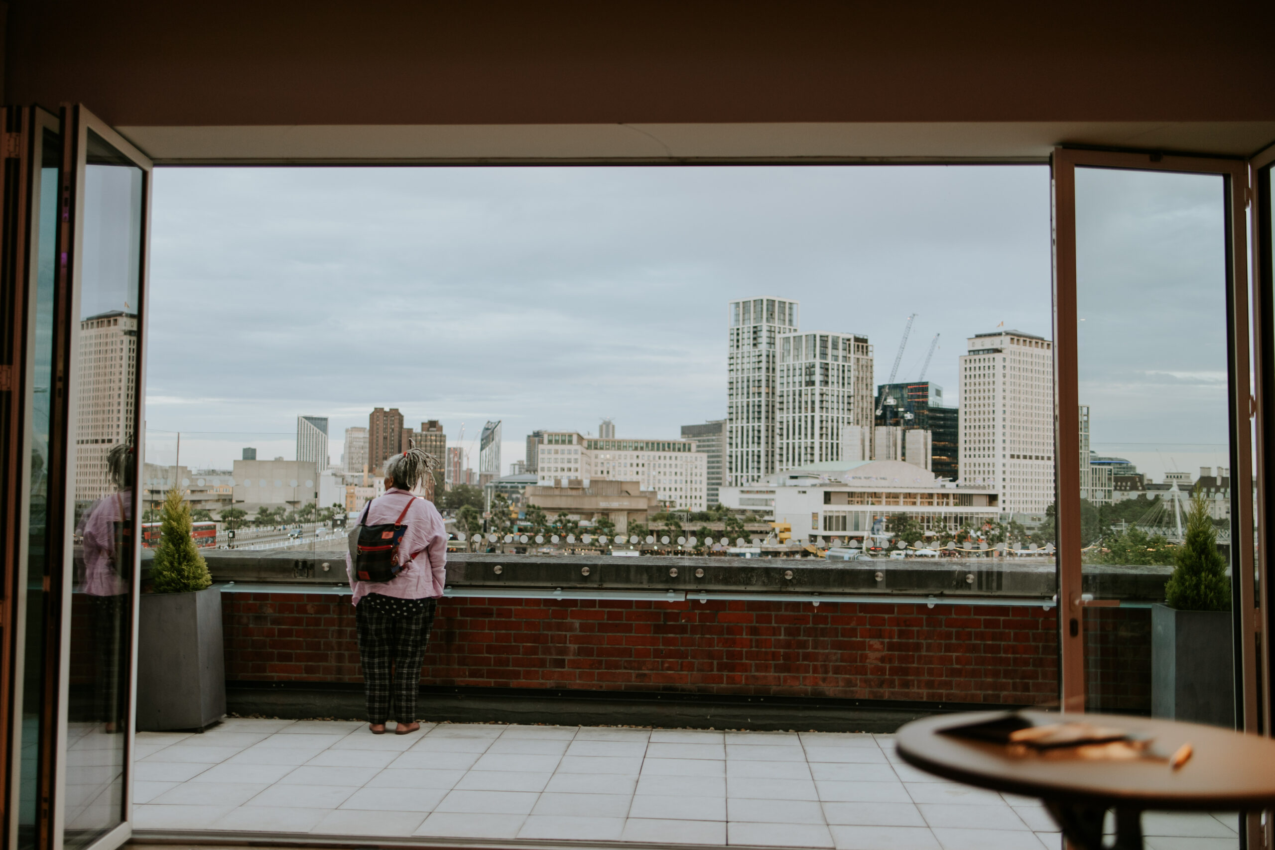 An actor standing on a balcony staring out at the London skyline