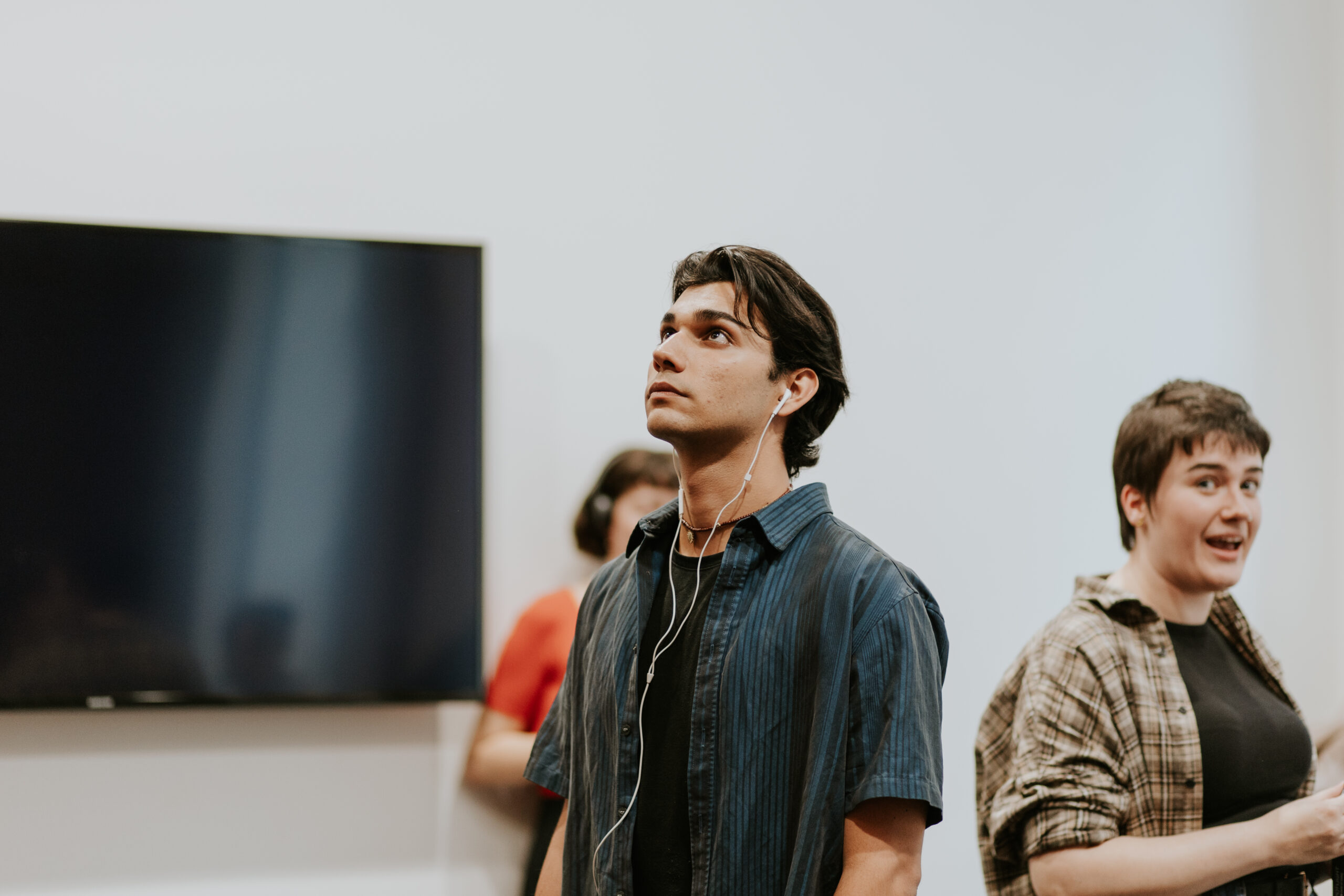 An actor with headphones in staring upwards as he prepares for his performance.