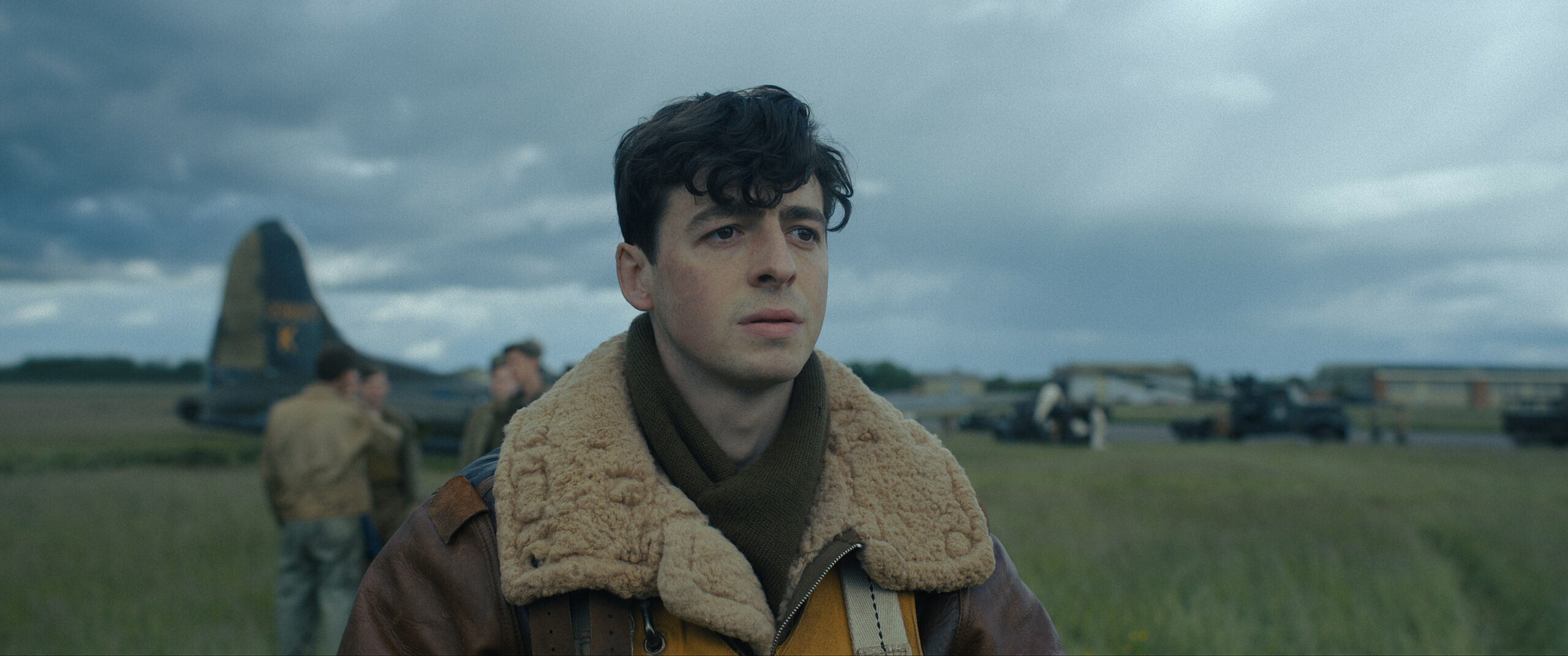 Anthony Boyle as 'Lt. Harry Crosby' in 'Masters of the Air' looking worried with an airfield in the background
