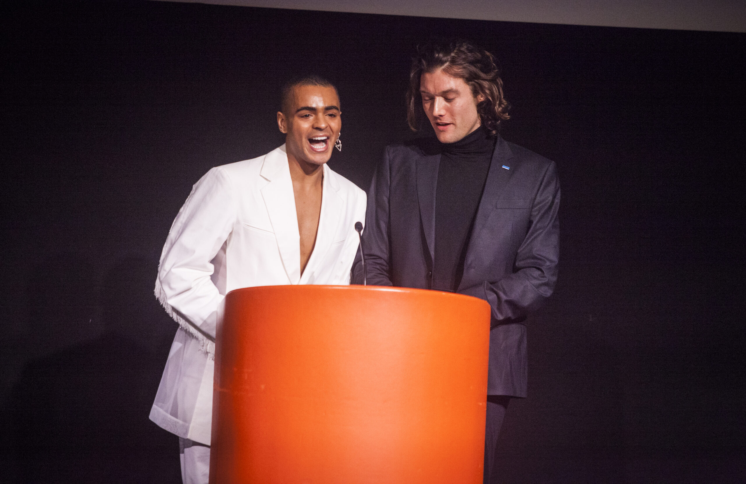 Layton Williams and Luke Millington-Drake standing at an orange podium during the CDG Awards 2024