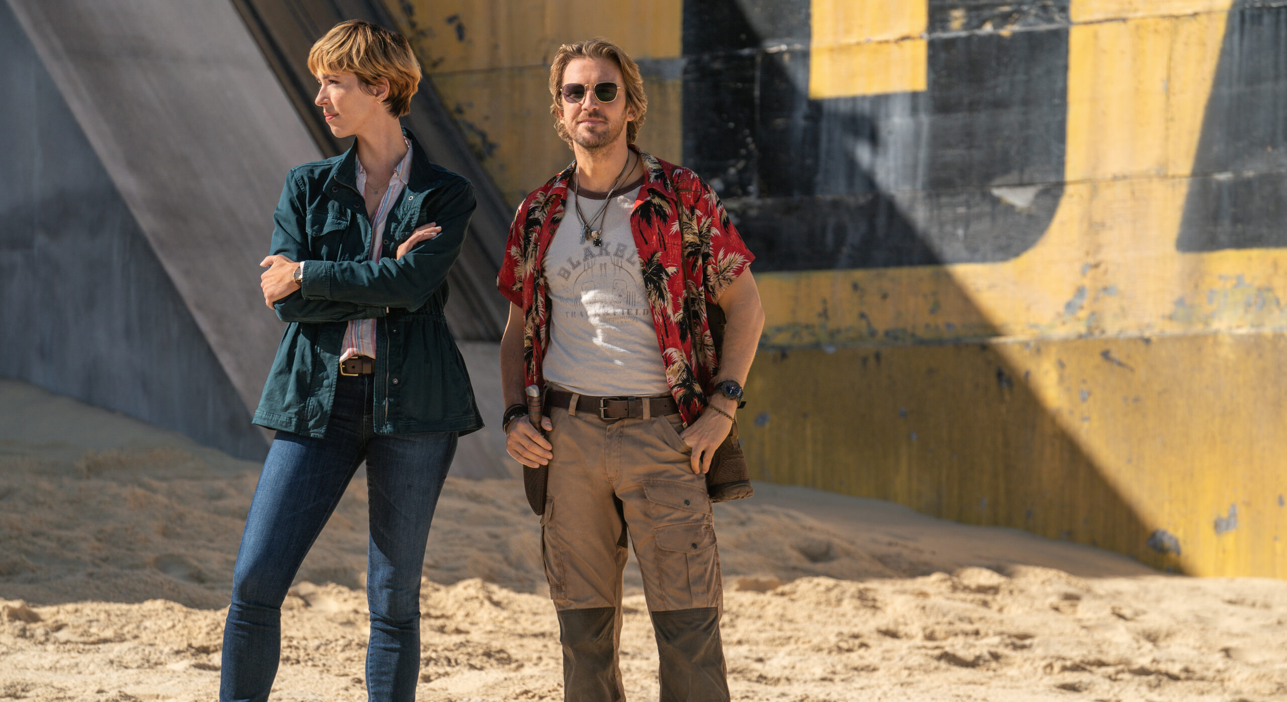 Rebecca Hall and Dan Stevens as 'Ilene Andrews' and 'Trapper' in 'Godzilla x Kong: The New Empire' standing on a sandy beach in filming location Australia