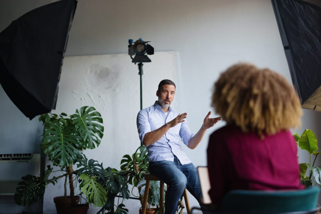 A man sitting next to plants speaking to a person