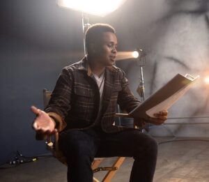 Man seated holding a script in a studio setting
