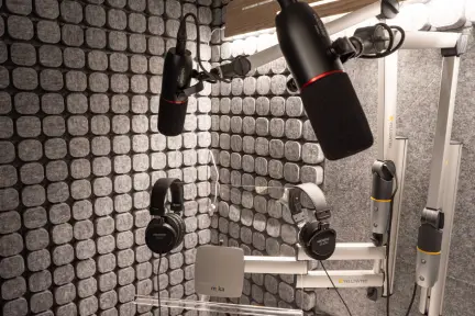 Professional microphones and headphones mounted in a soundproofed voiceover booth