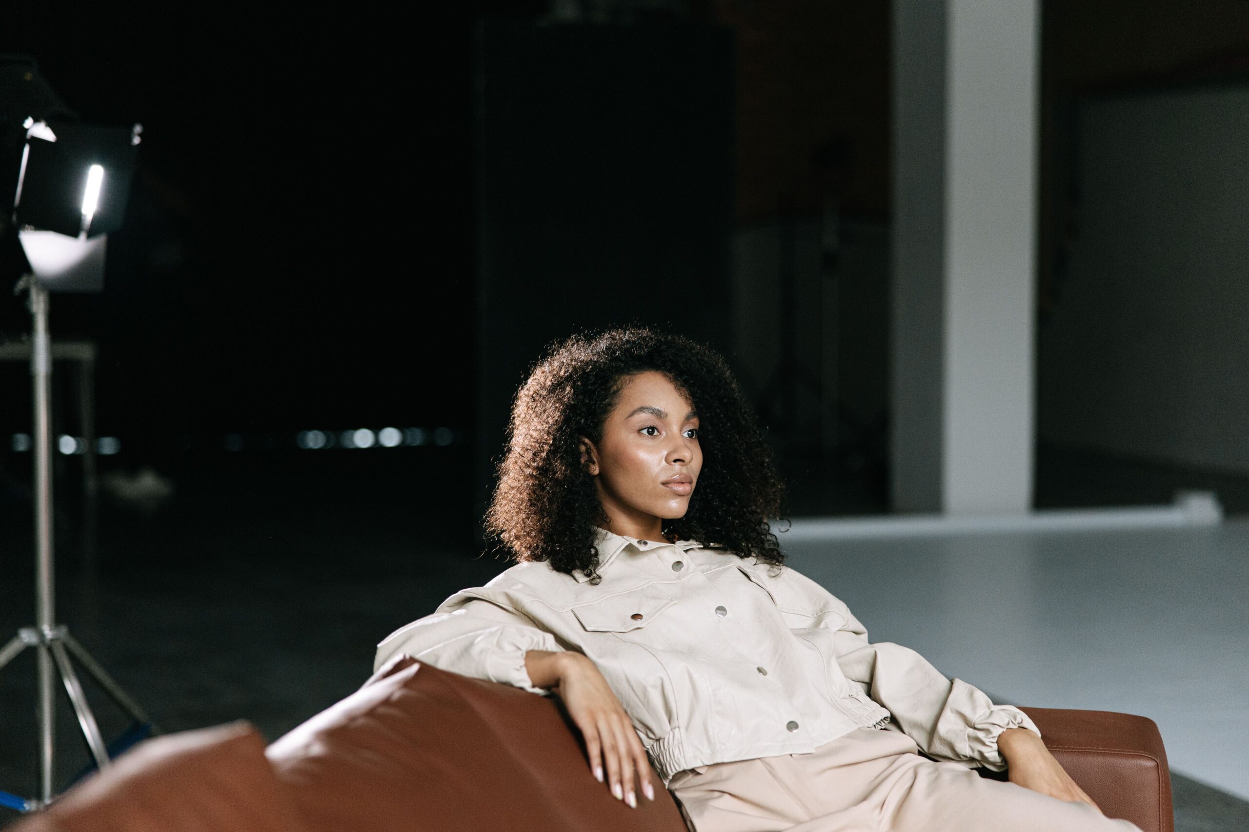 Woman reclining on a sofa with film set lighting behind her